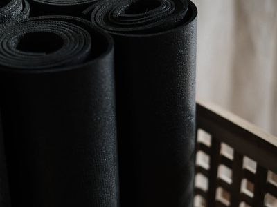 A blue yoga mat rolled up in a modern gym corner.