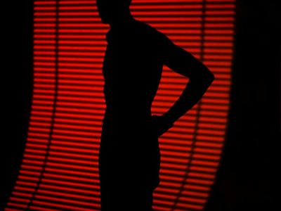 Abstract silhouette of a person stretching against a dark wall.